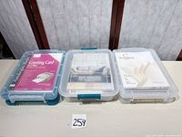 Three plastic latch boxes containing the three cardstock packs