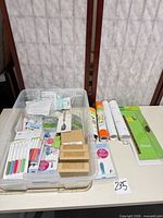 Overall lot view on table showing bin, trimmer, vinyl rolls, pens, blade boxes