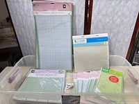Bin containing multiple Cricut cutting mats and YourStory laminating pouches
