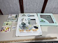 Group shot of all Slice items: two hands-free kit boxes, glass cutting mat box, design card