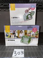 Two boxed Xyron items: Creative Station machine and 18 ft refill cartridge