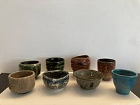 Front view of all eight tea bowls showing variety of glazes and shapes