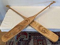 two crossed carved wood paddles showing overall length and finish