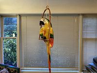 Parrot hanging from perch in window setting