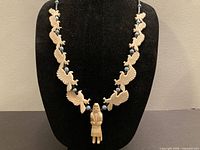 Full view of necklace on bust showing layout of carved birds, central Kachina, blue beads