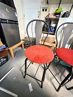 Front view of one black metal bar stool with red seat