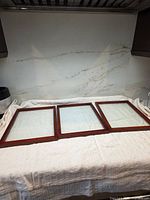 Three identical wooden double-glass frames laid out side by side on a cloth