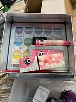 Watercolor palette, brush, craft pen and beads inside tin