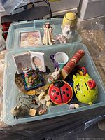 Open bin showing figurines, banks, fairy, mug, kaleidoscope and trinkets
