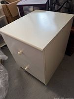 Three-quarter view of white IKEA nightstand showing top, right side and knobs