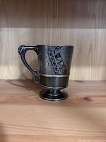 Front view of engraved silver cup on pedestal base