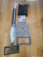Full steam mop with cord, pads, frame, box, bag displayed on floor