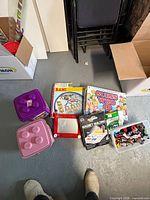Overview of lot with board games, Etch A Sketch, Magnet Building box, Lego pieces bin, Lego brick storage cases