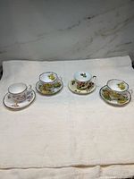 Four floral teacup and saucer sets displayed on cloth