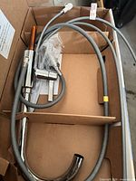 Faucet components in box showing spout, body, hoses and hardware