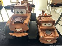Front view of both Tow Mater toys showing size difference and condition
