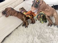 Five dinosaur figures lined on white rug