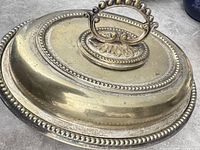 Top view of oval nickel-silver serving dish with lid and ornate handle