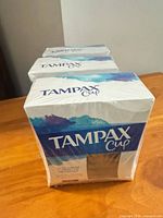 Front angle showing three shrink-wrapped Tampax Cup boxes