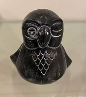 front view of black soapstone owl with one eye closed and incised feather pattern