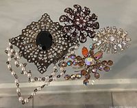 All four brooches laid flat on glass surface showing overall designs