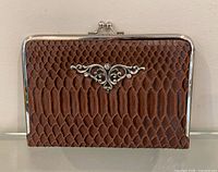 Front view of brown embossed leather clutch photo album showing metal frame and filigree ornament