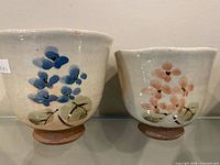 Front view of both stoneware cups showing floral designs