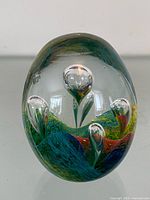 Front view of clear egg-shaped paperweight showing internal colourful floral design