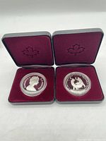 Two presentation cases open showing both coins in capsules