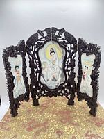 Full view of three-panel carved wood screen standing on patterned surface