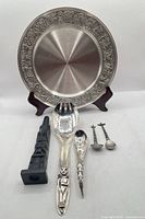 Group shot showing all six items: pewter plate, totem pole sculpture, large salad fork, ladle spoon, two small spoons