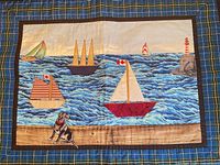 Full view of quilted wall hanging with plaid border and nautical scene