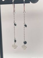 Full view of both earrings hanging to show length and chain