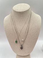 Three necklaces with pendants displayed on bust