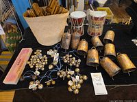 Overview of cowbells, whistles in basket, mini bongos, bell chimes on table