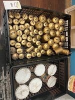 Two stacked crates showing numerous brass cowbells and several small hand drums