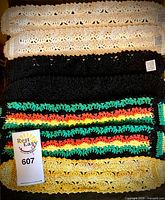 Stacked crocheted strips in various colors including cream, black, multicolor stripes and yellow-white