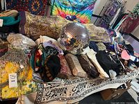 table view with disco ball, assorted hats, clothing pile and patterned textile