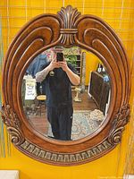 Front view of oval carved wooden wall mirror