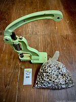 Hand lever press next to bag of rivets on wood floor