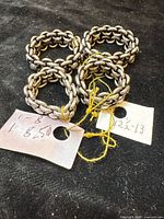 Four sterling silver chain-link rings on black surface with size tags