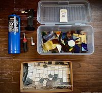 All lot items laid out: propane cylinder, two torches, attachment, plastic container with stained glass, box with glass squares