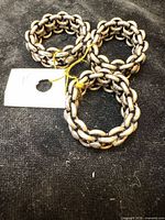 Three chain-link sterling rings with attached size tag on black background