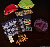 All items laid out: two caps, two bandannas, wallet, coin purse, stowaway backpack pouch, two bell anklets, wooden knocker chime