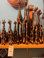 Front view of full set of giraffe and cat carvings on shelf