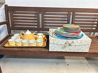 Overall lot on bench: teaset, storage box, stack of plates