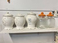 Shelf with four white ceramic canisters and two glass canisters