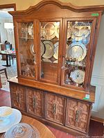 Full view of assembled two-piece wood china cabinet showing buffet base, glass hutch, decorative panels, metal pulls