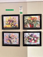 Set of four black framed floral prints mounted on wall