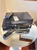 Stacked view of Panasonic VCR on Samsung DVD player with both remotes